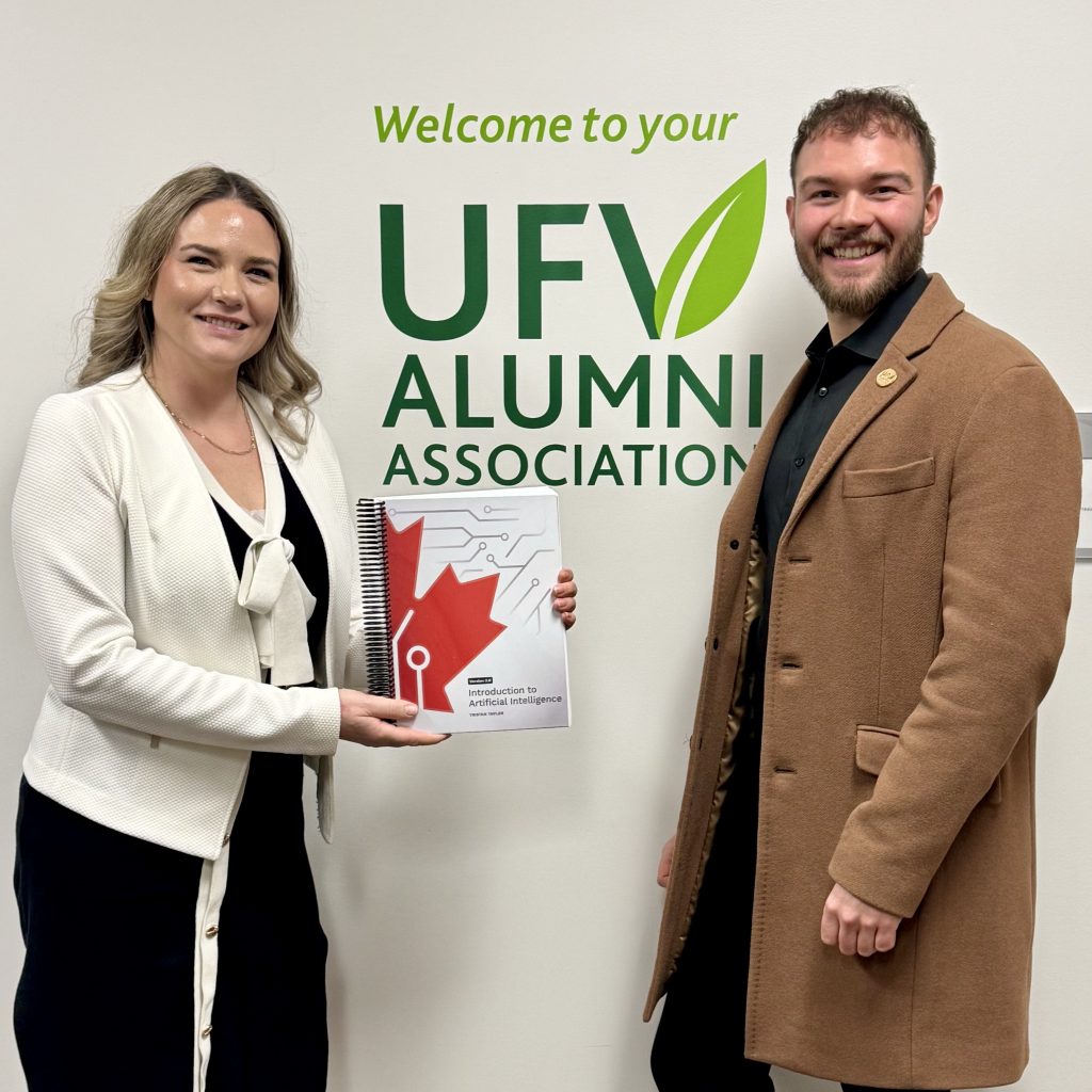 Whitney Fordham holding the Introduction to Artificial Intelligence textbook with Tristan Taylor at UFV Alumni Association