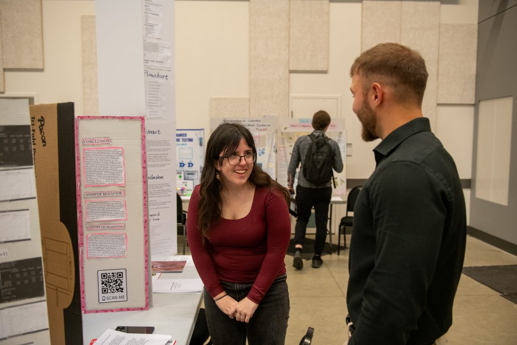 Woman and man chatting beside project posters at a science fair