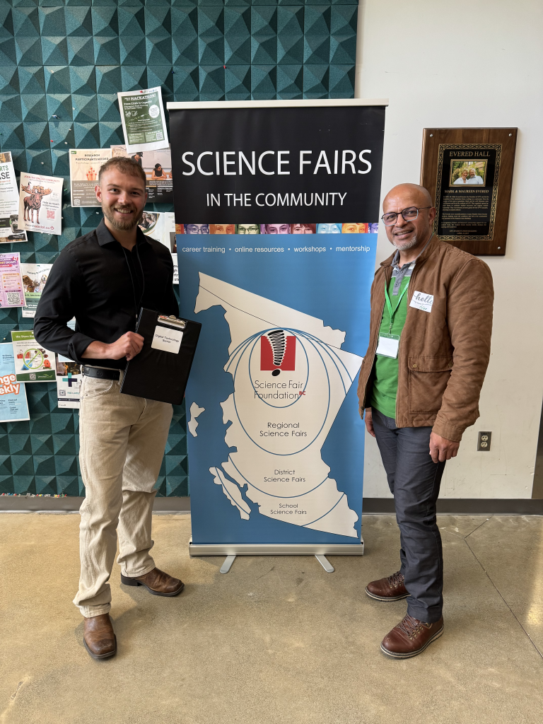 Two men beside a Science Fairs in the Community banner